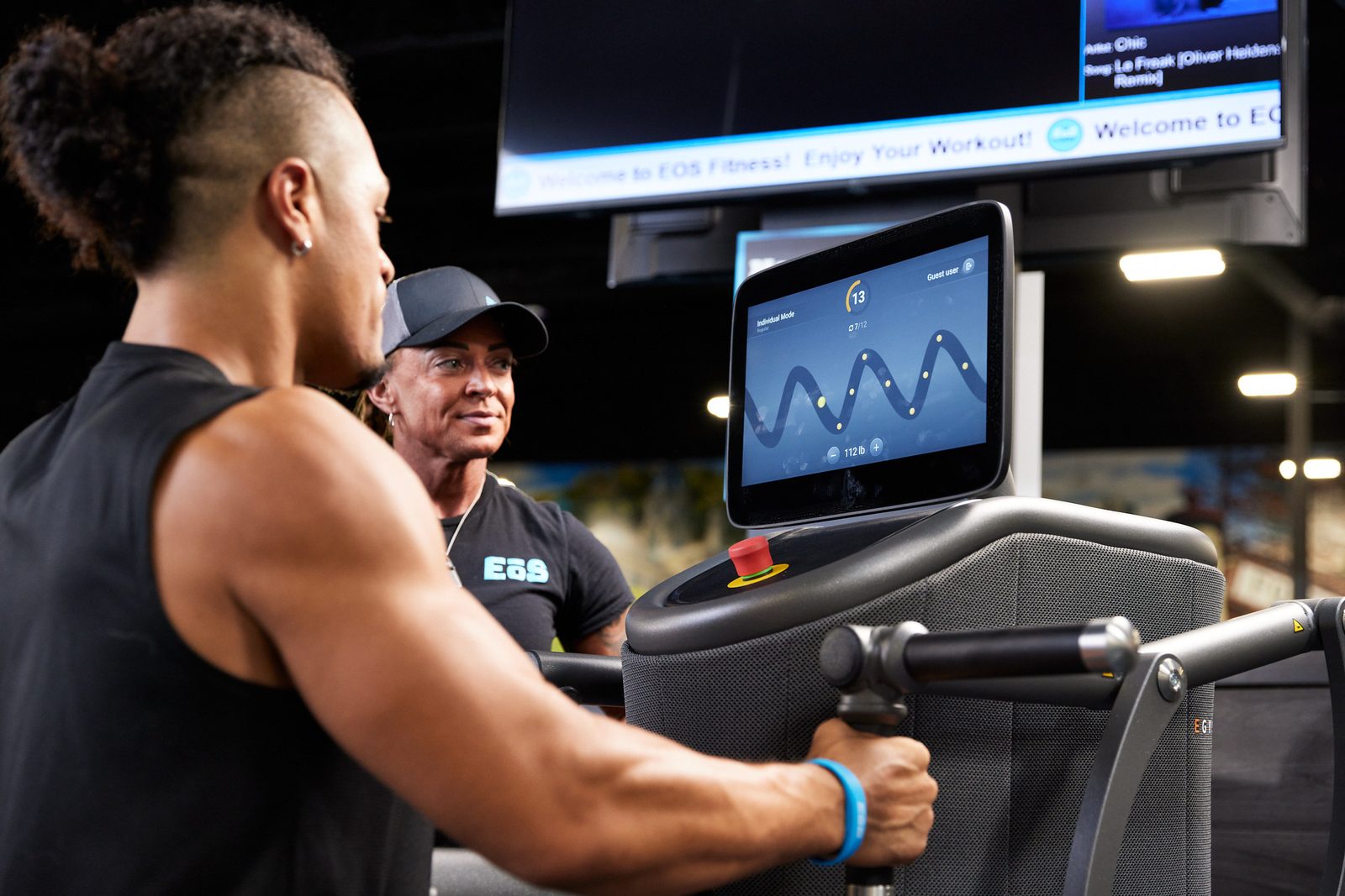 EōS Fitness member training on an EGYM machine with a coach