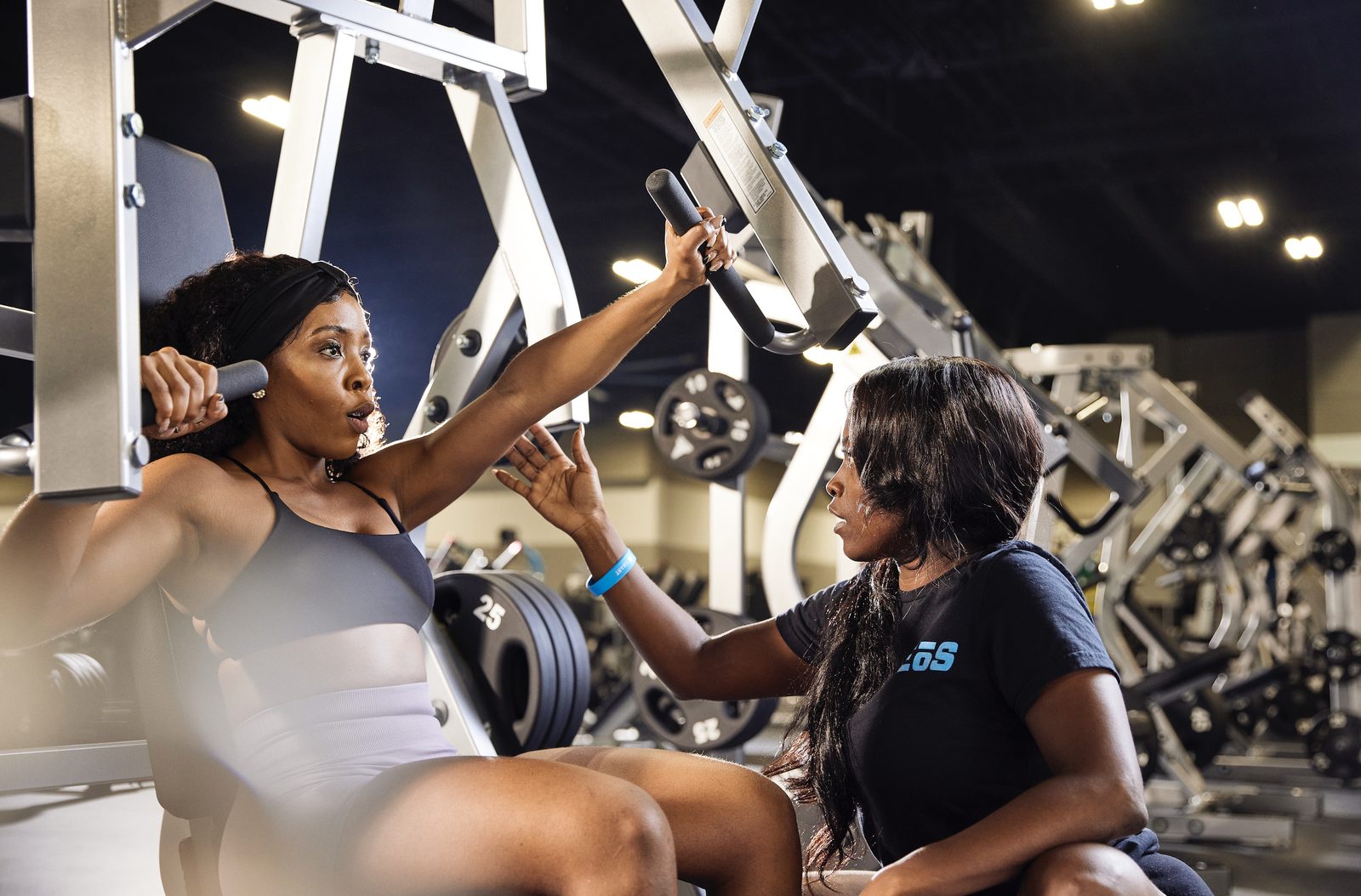 EōS Fitness trainer coaching a member through a chest press